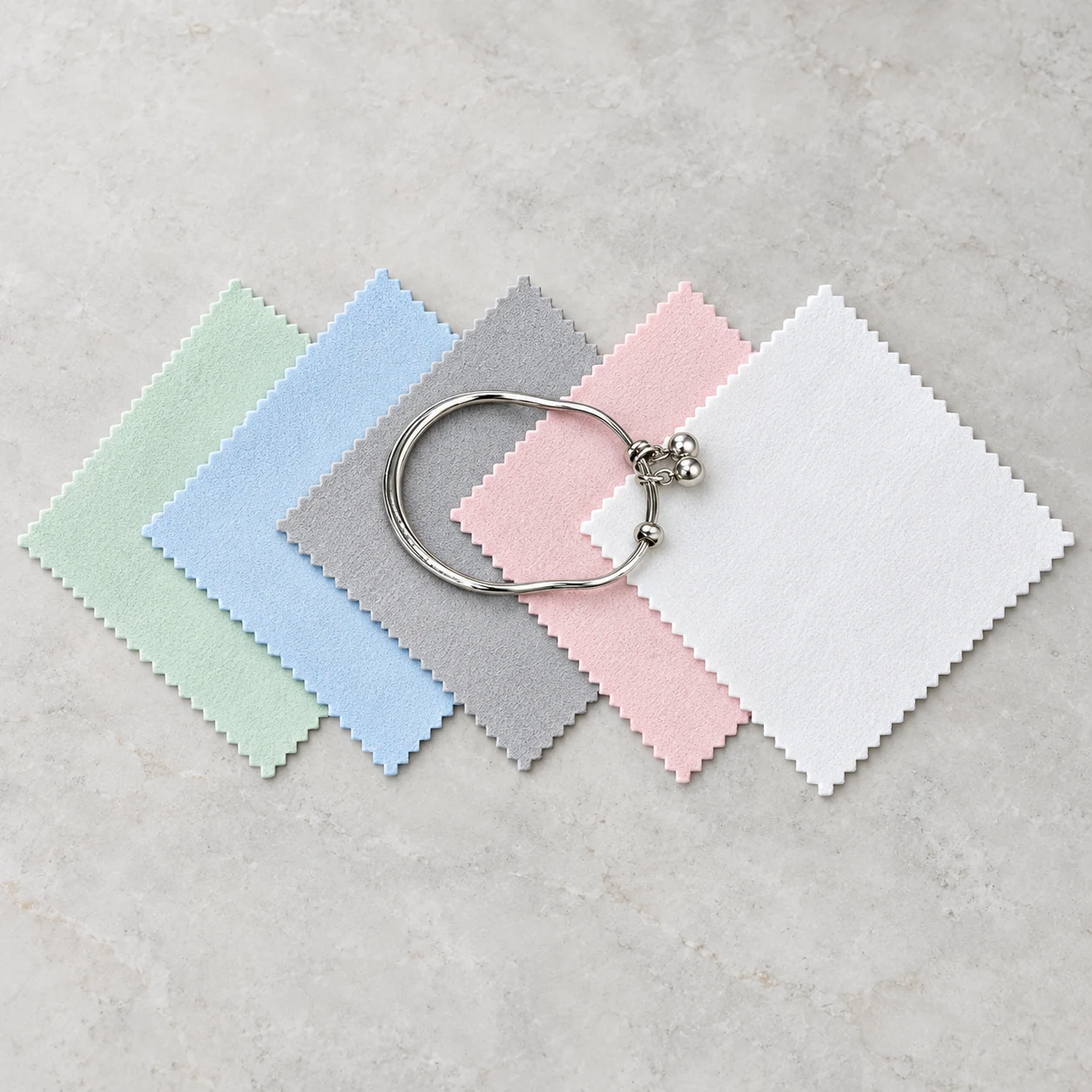 Silver bracelet displayed on five assorted-color 15 x 15 cm jewelry polishing cloths