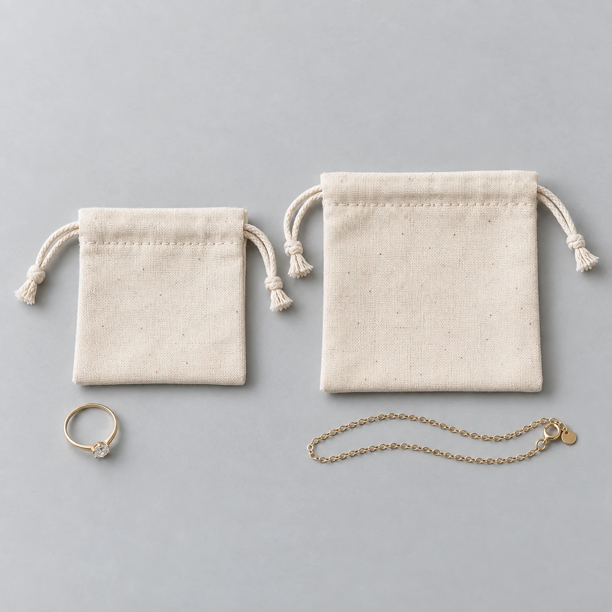 Side-by-side size comparison of 6 x 6 cm and 8 x 8 cm cotton drawstring jewelry pouches