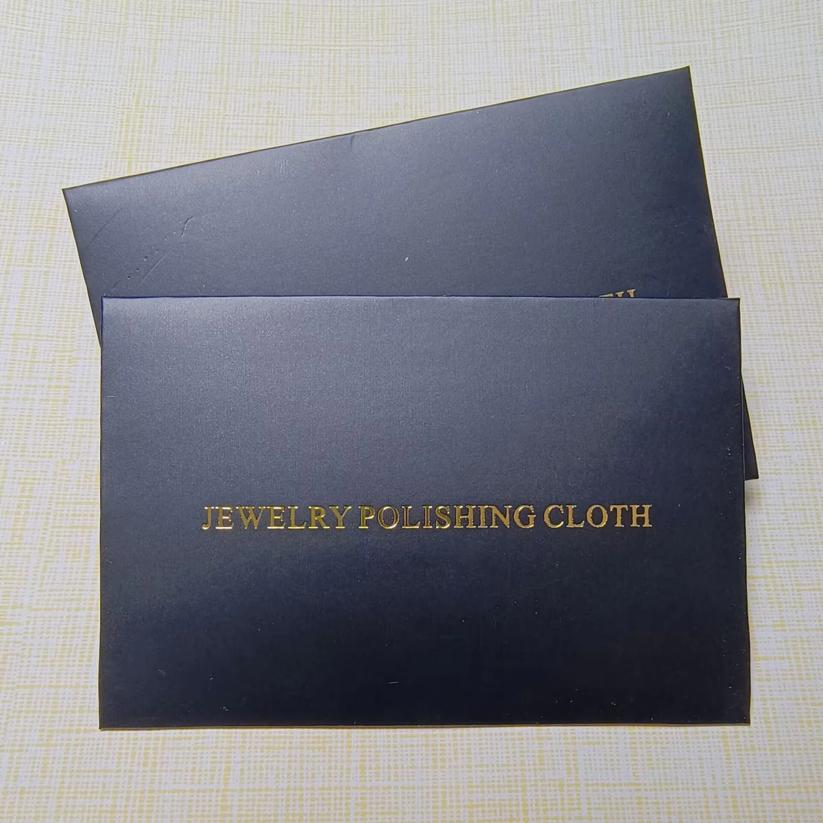 Front view of a black envelope with gold foil Jewelry Polishing Cloth lettering
