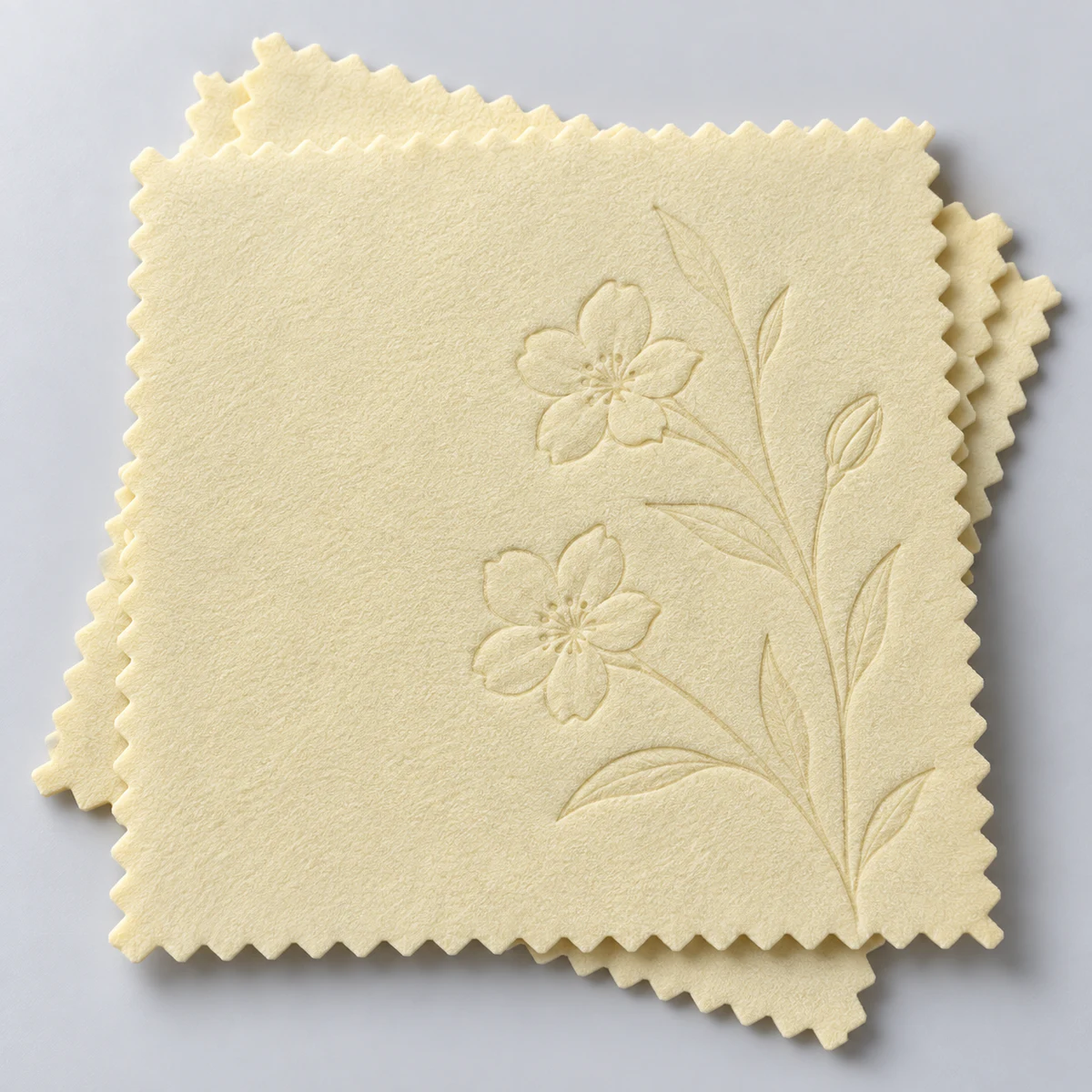 Pale yellow silver polishing cloths with an embossed floral stem design