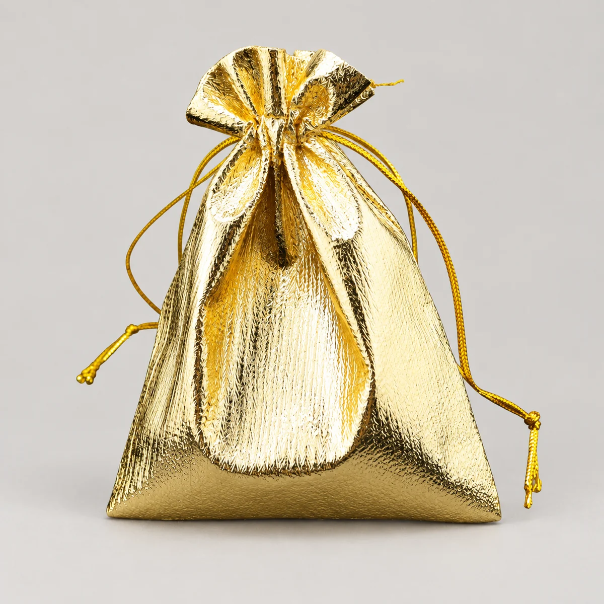 Gold metallic drawstring jewelry pouch with braided cords on a studio background