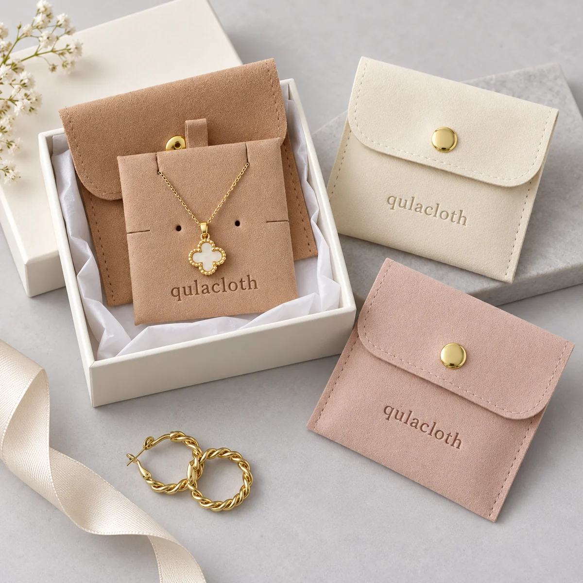 Custom logo microfiber jewelry pouches with gold snap buttons and an ivory gift box
