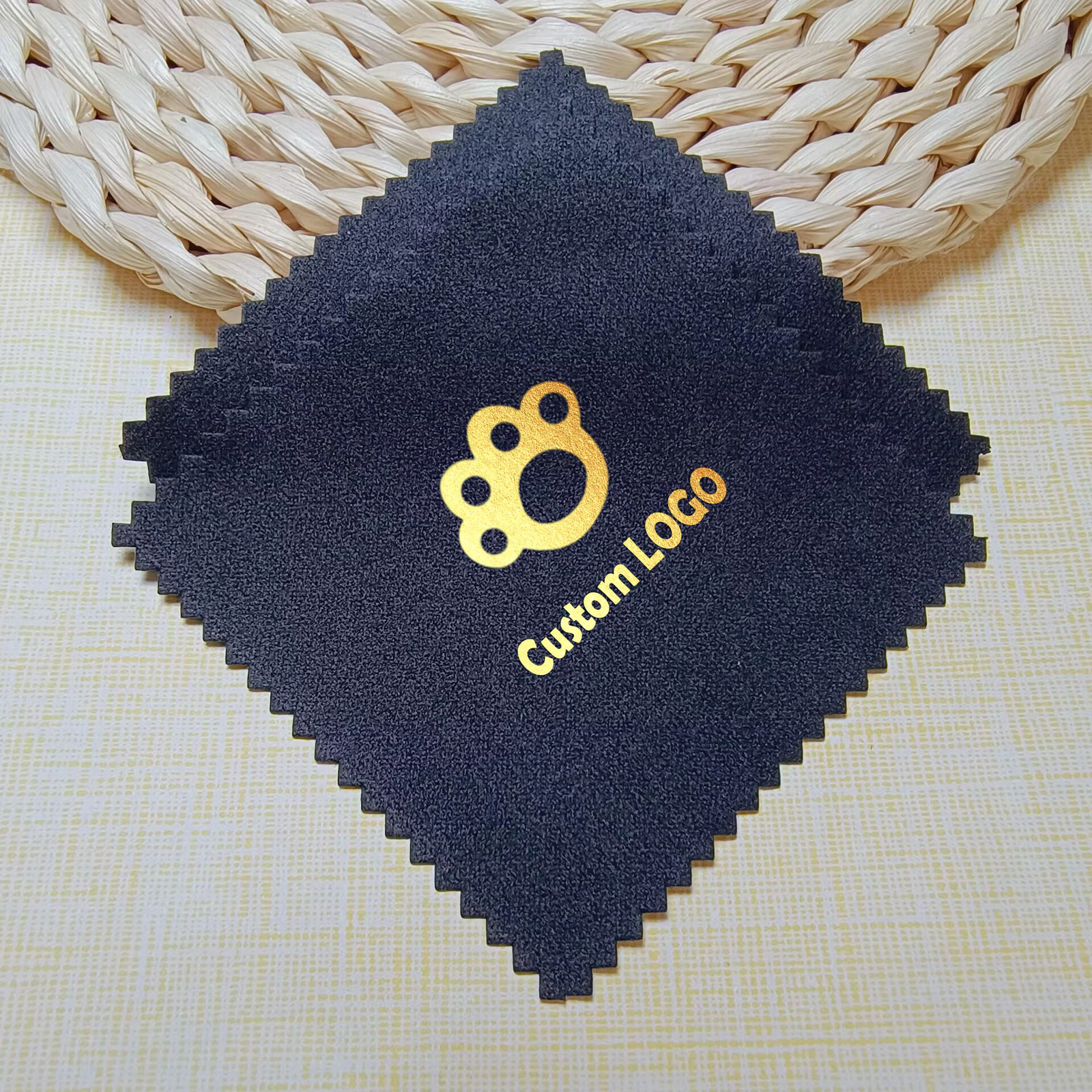 Black jewelry polishing cloth with a metallic gold paw logo and zigzag edges