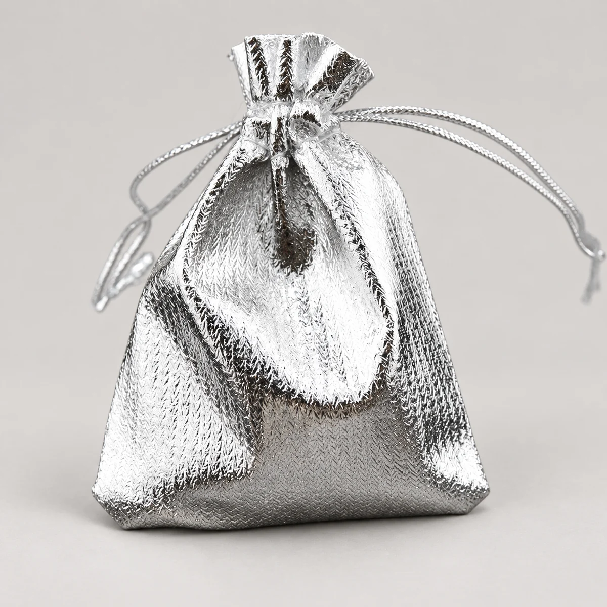 Silver metallic drawstring jewelry pouch with braided cords and gathered closure