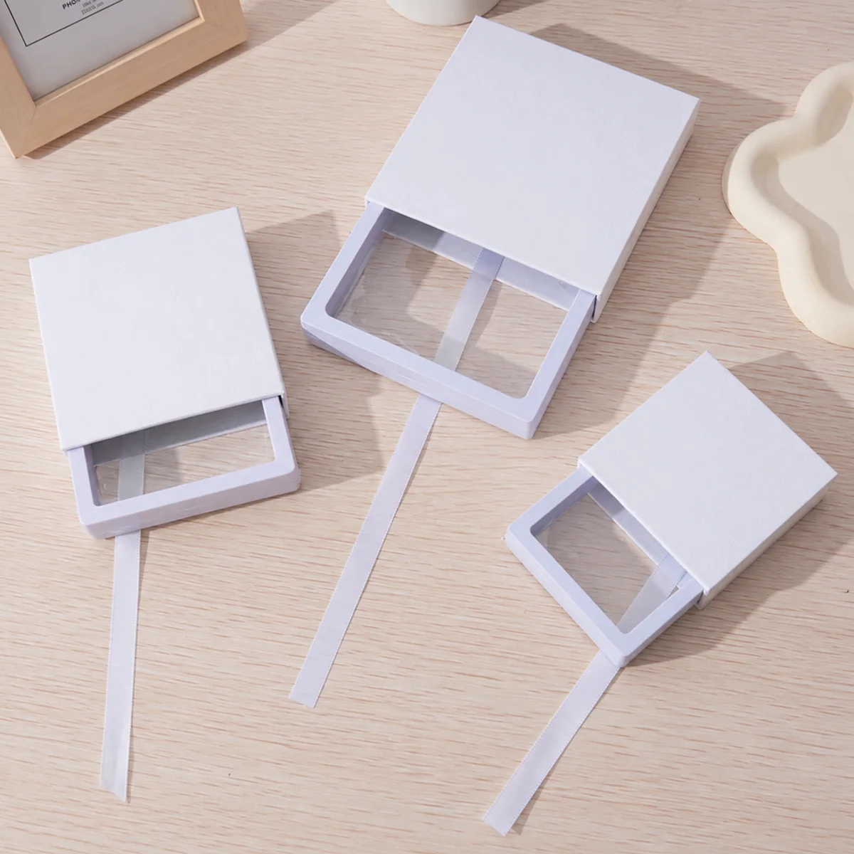 Three white sliding drawer jewelry boxes with clear suspension film windows and ribbon pulls