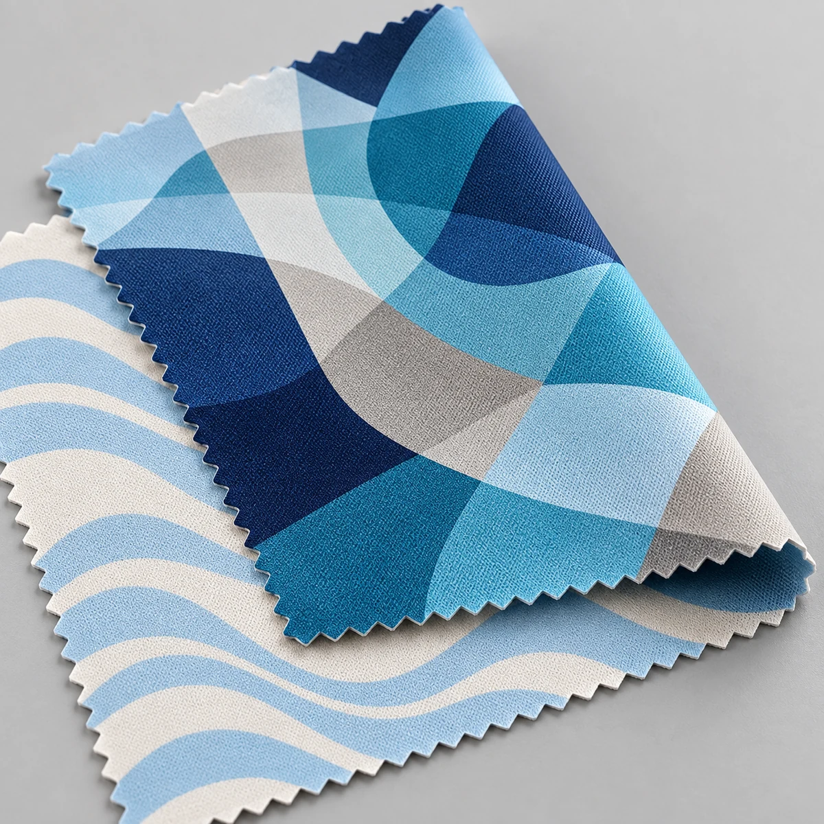 Close-up of two full-color printed microfiber lens cloths showing fine weave folds and zigzag edges