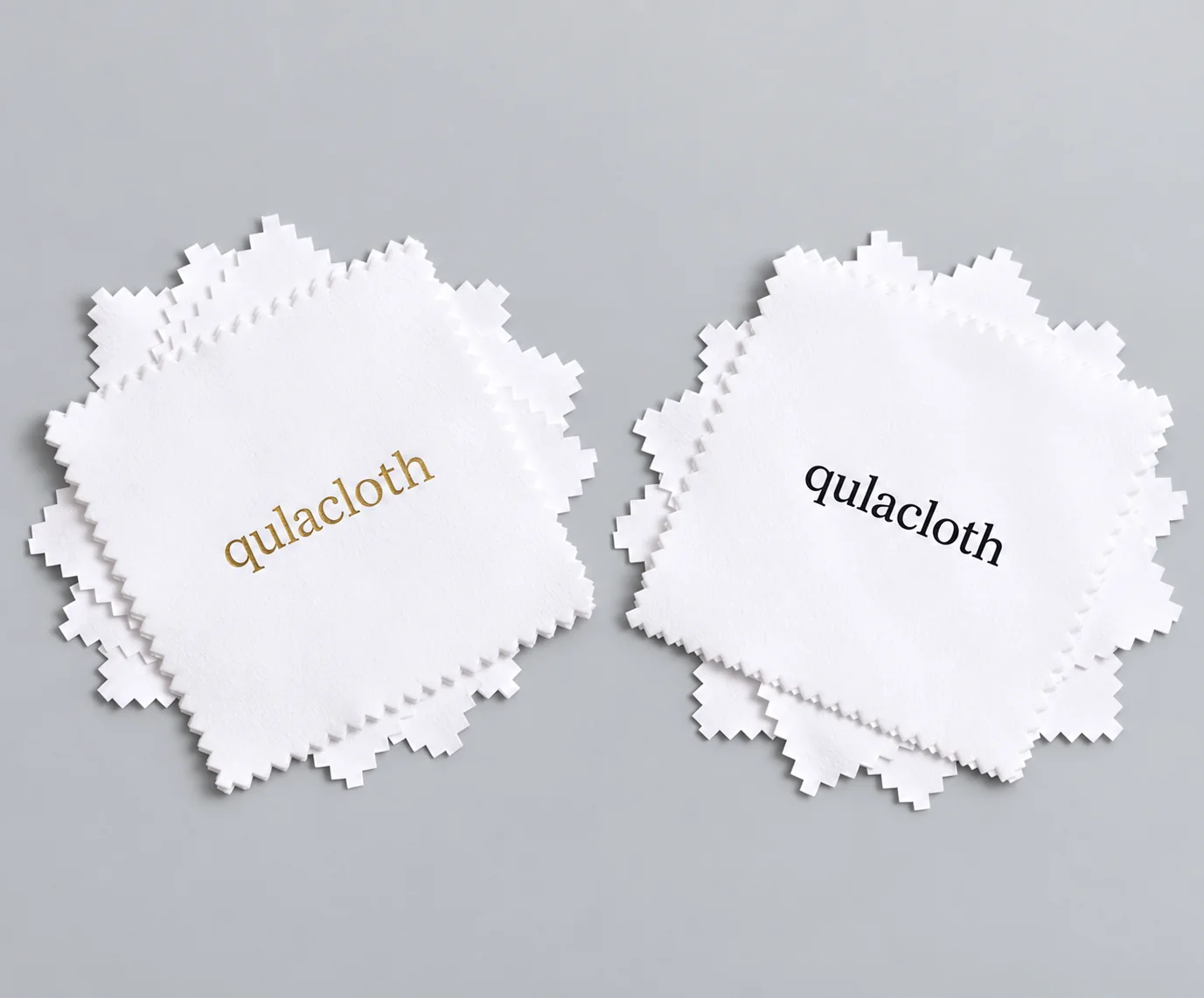 White jewelry polishing cloth stacks comparing metallic gold and black Qulacloth logos