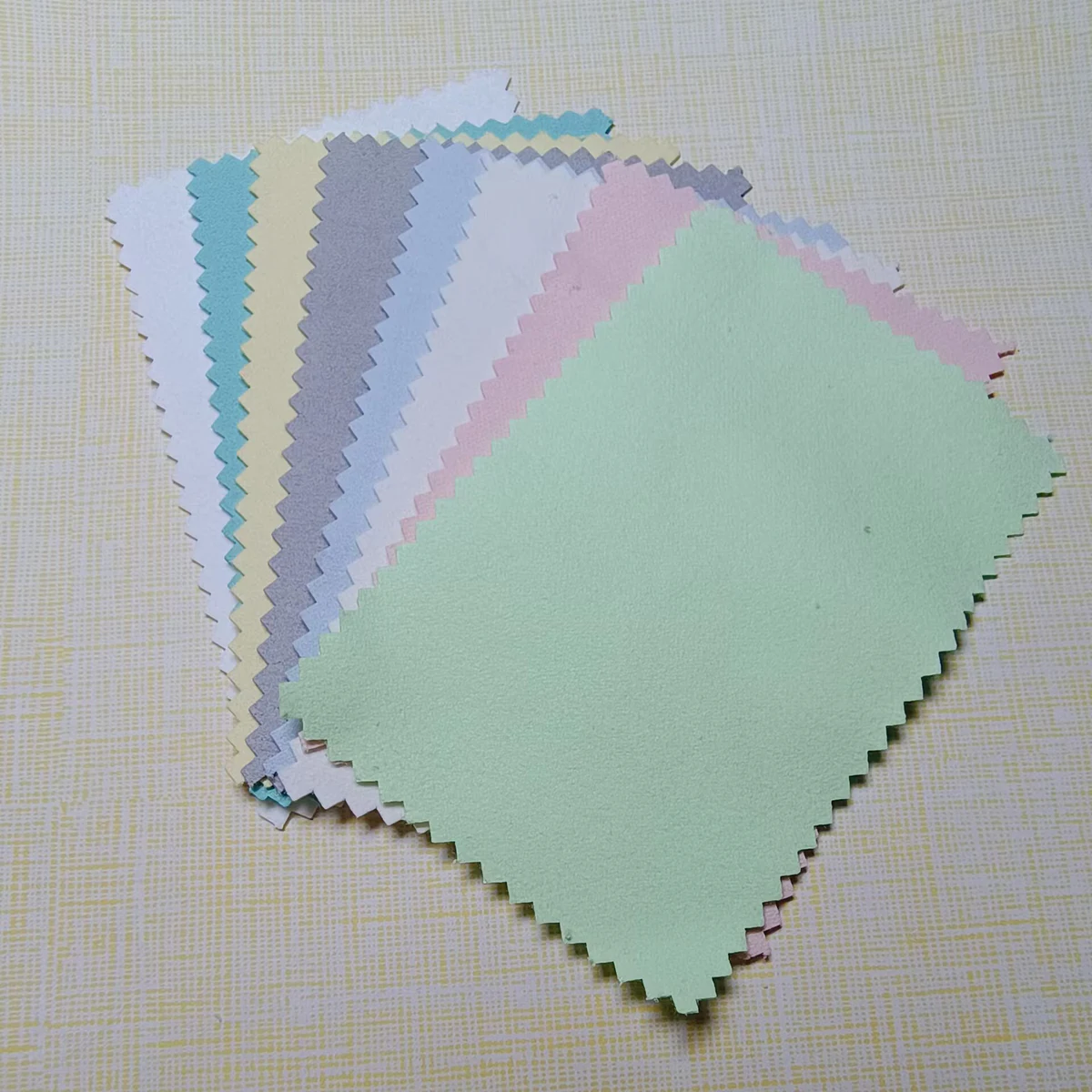 Assorted pastel 6.5 x 10 cm rectangular silver polishing cloths with a mint green cloth in front