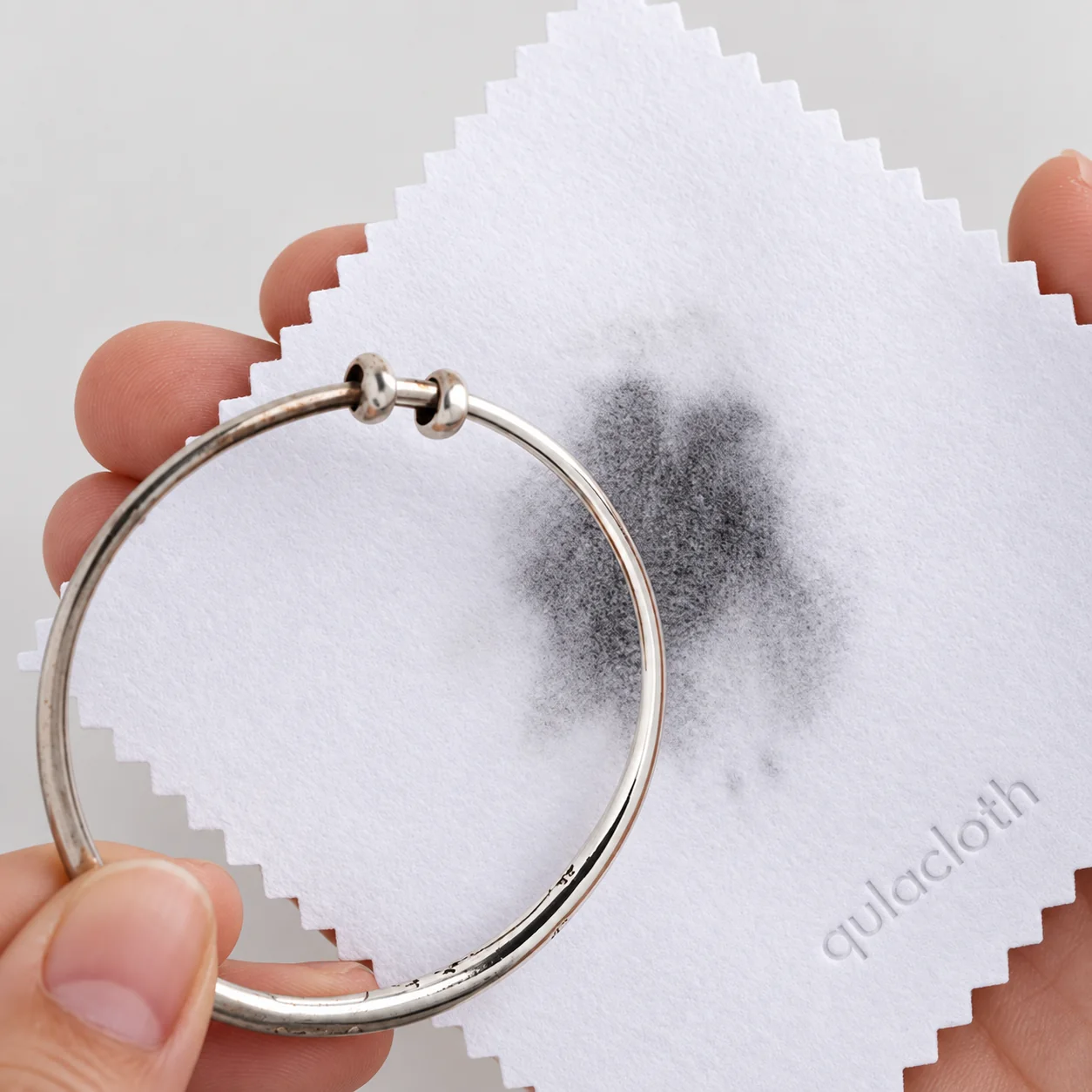 White silver polishing cloth showing dark residue after polishing a silver bangle