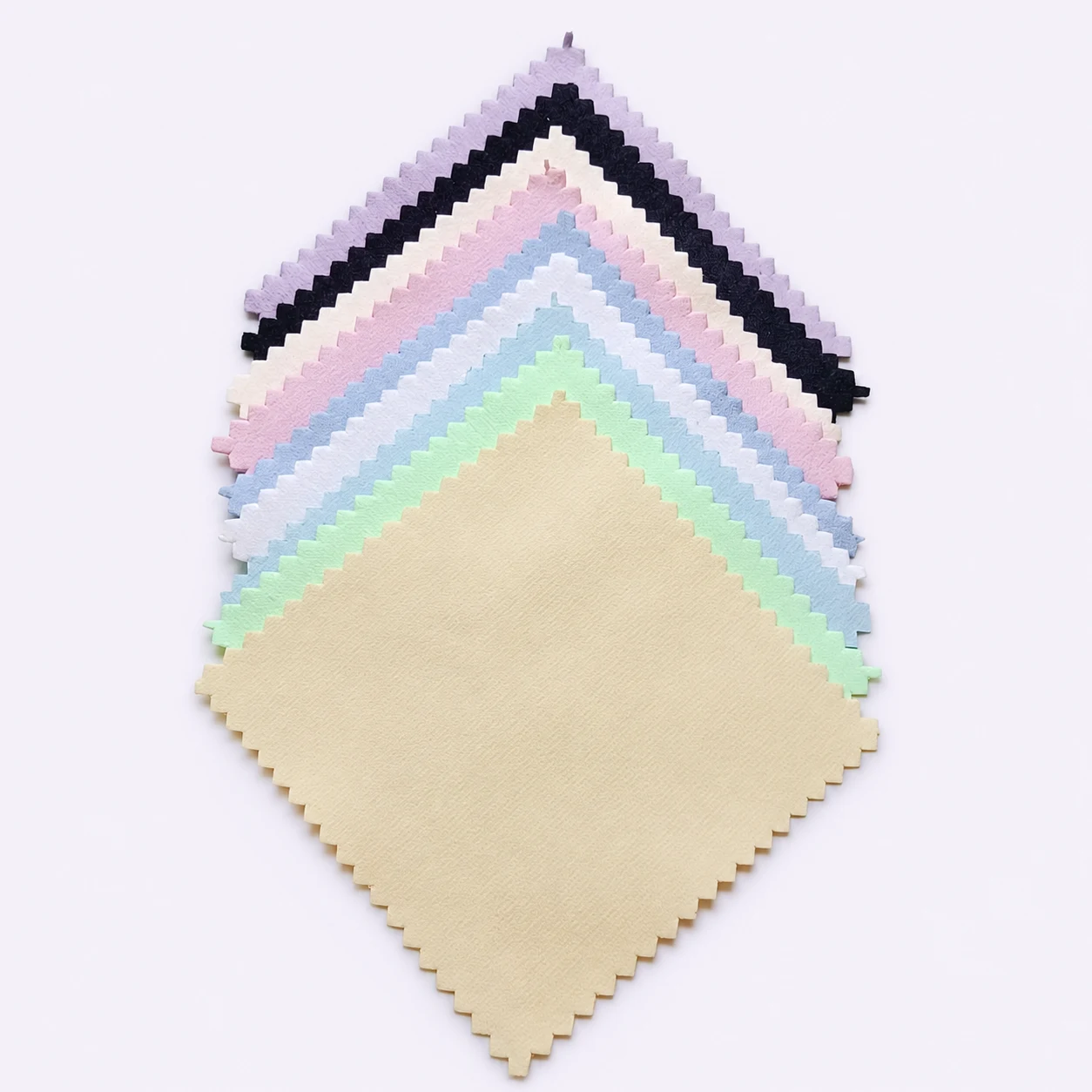 Stack of square jewelry polishing cloths in beige, green, blue, pink, black and lavender